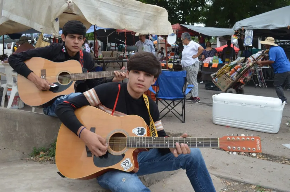 Virlan y Brandon, salen con su guitarra para alegrar a las personas, quienes en agradecimiento les regalan una moneda que les ayuda a pagar sus estudios. Fotos: Juan Madrigal